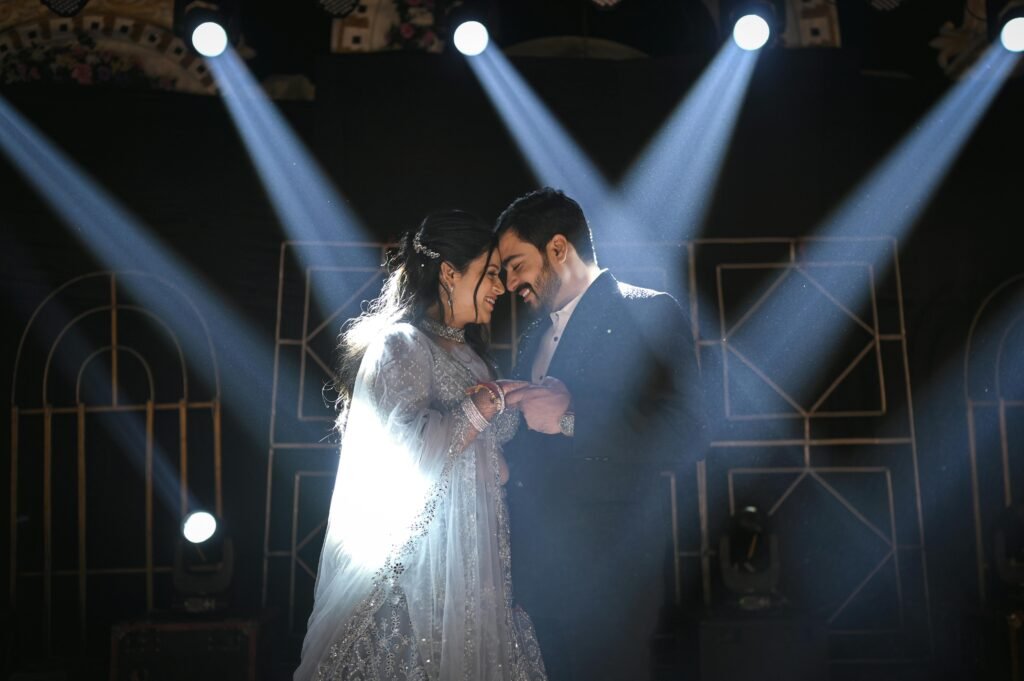 A smiling couple enjoys a romantic dance under dramatic spotlights.