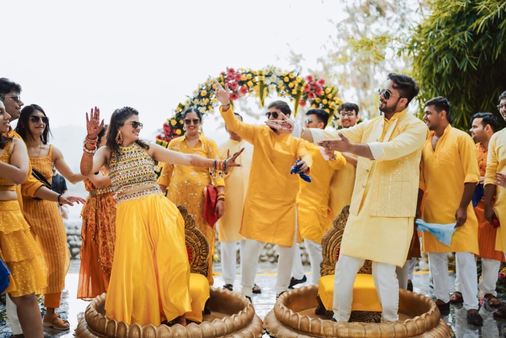 Joyful Indian wedding with guests dancing in traditional attire outdoors.
