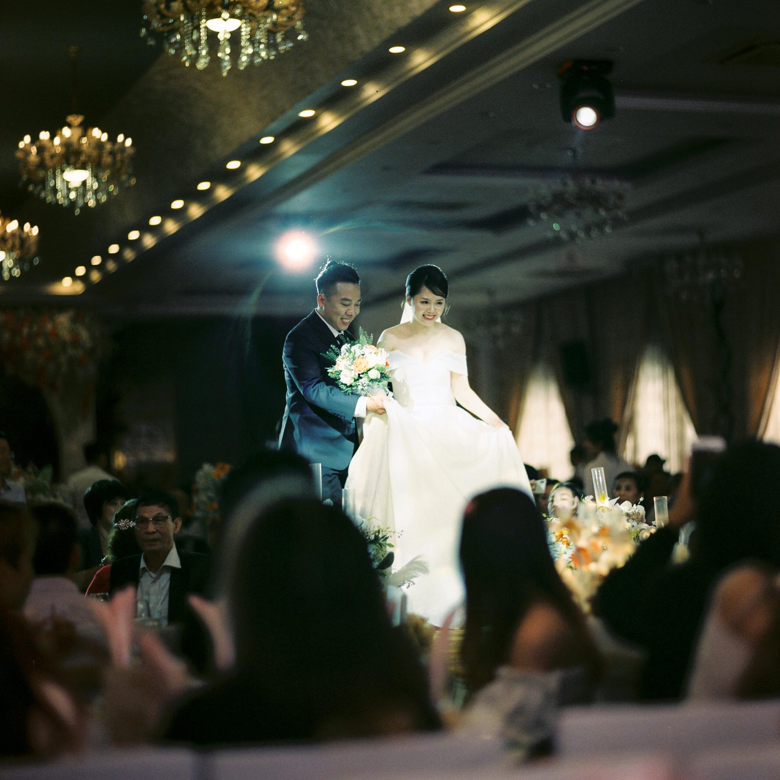 A bride and groom elegantly walk through their wedding reception in Hanoi, Vietnam.