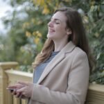 Smiling woman enjoying a moment of happiness outdoors during fall season.